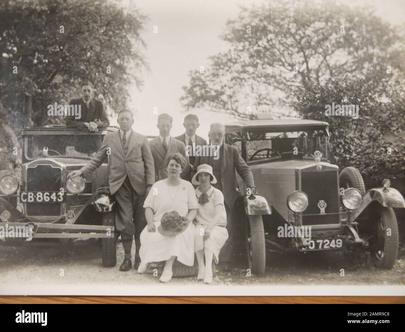 Copy of an old photo of two classic cars (vehicle reg CB 8643) and a group of people posed beside them Stock Photo