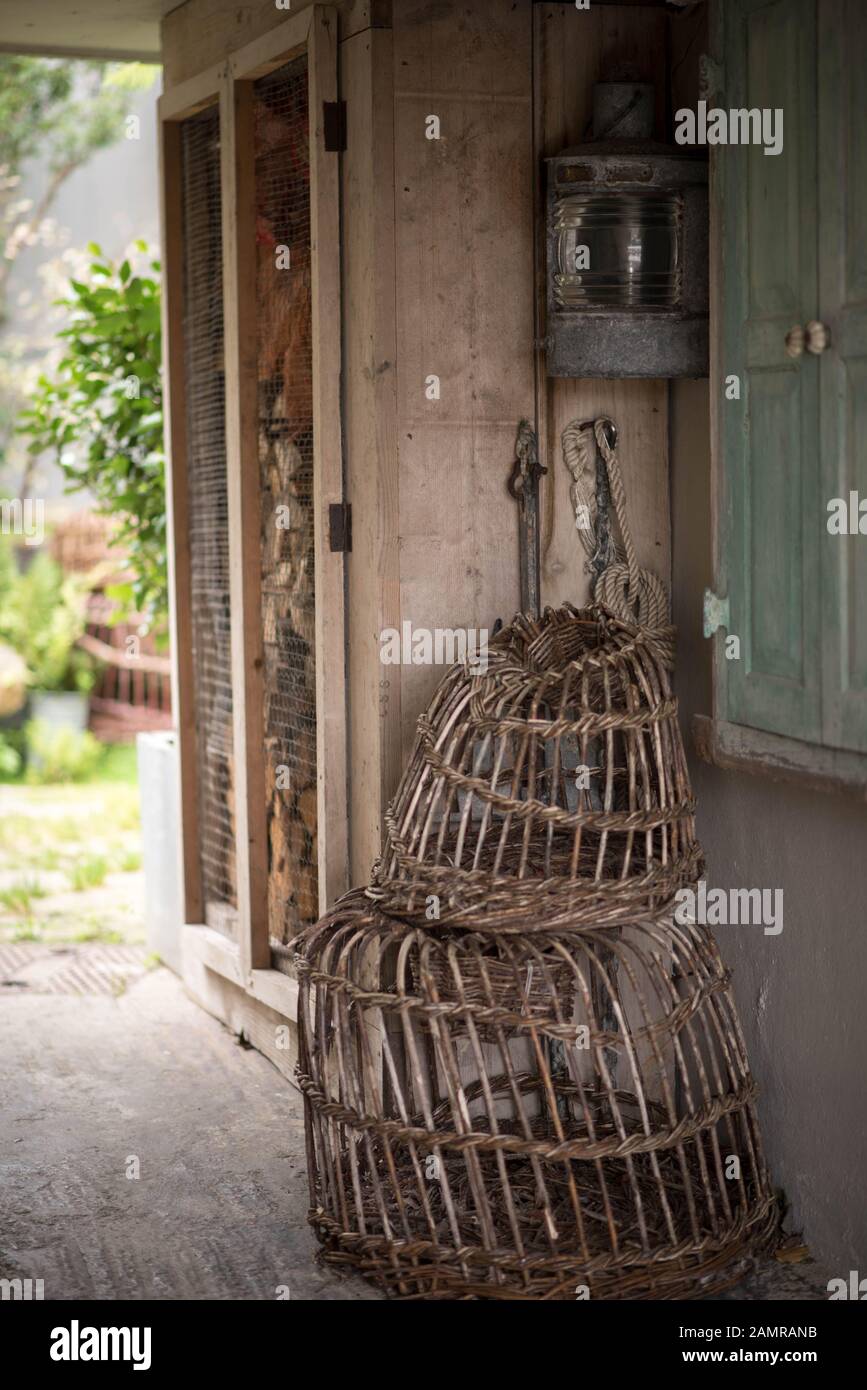 Lobster pots and lantern awaiting use perched by a house in an English fishing village Stock Photo