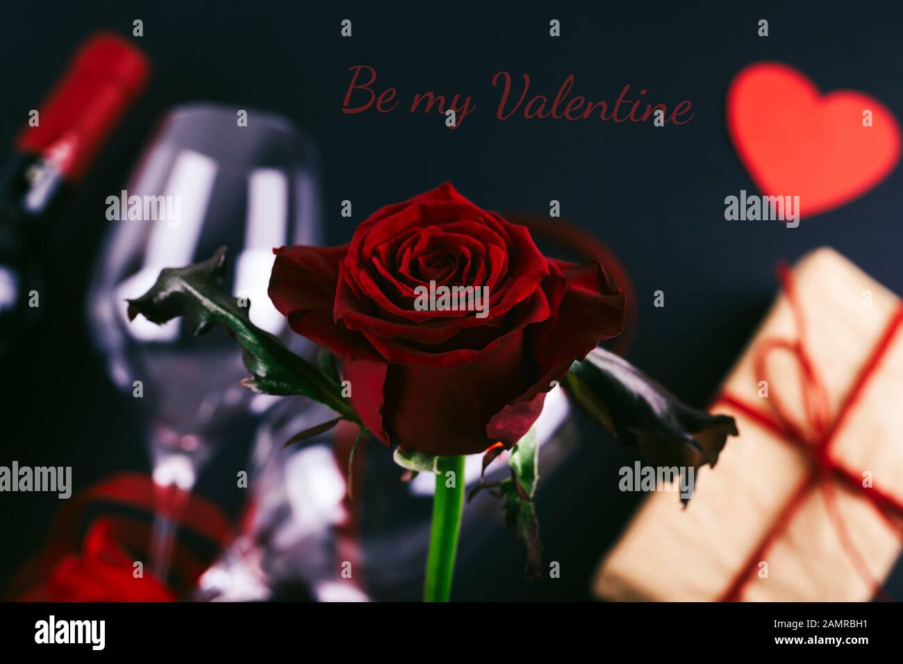 Beautiful red rose on festive background with bottle of wine, glasses ...