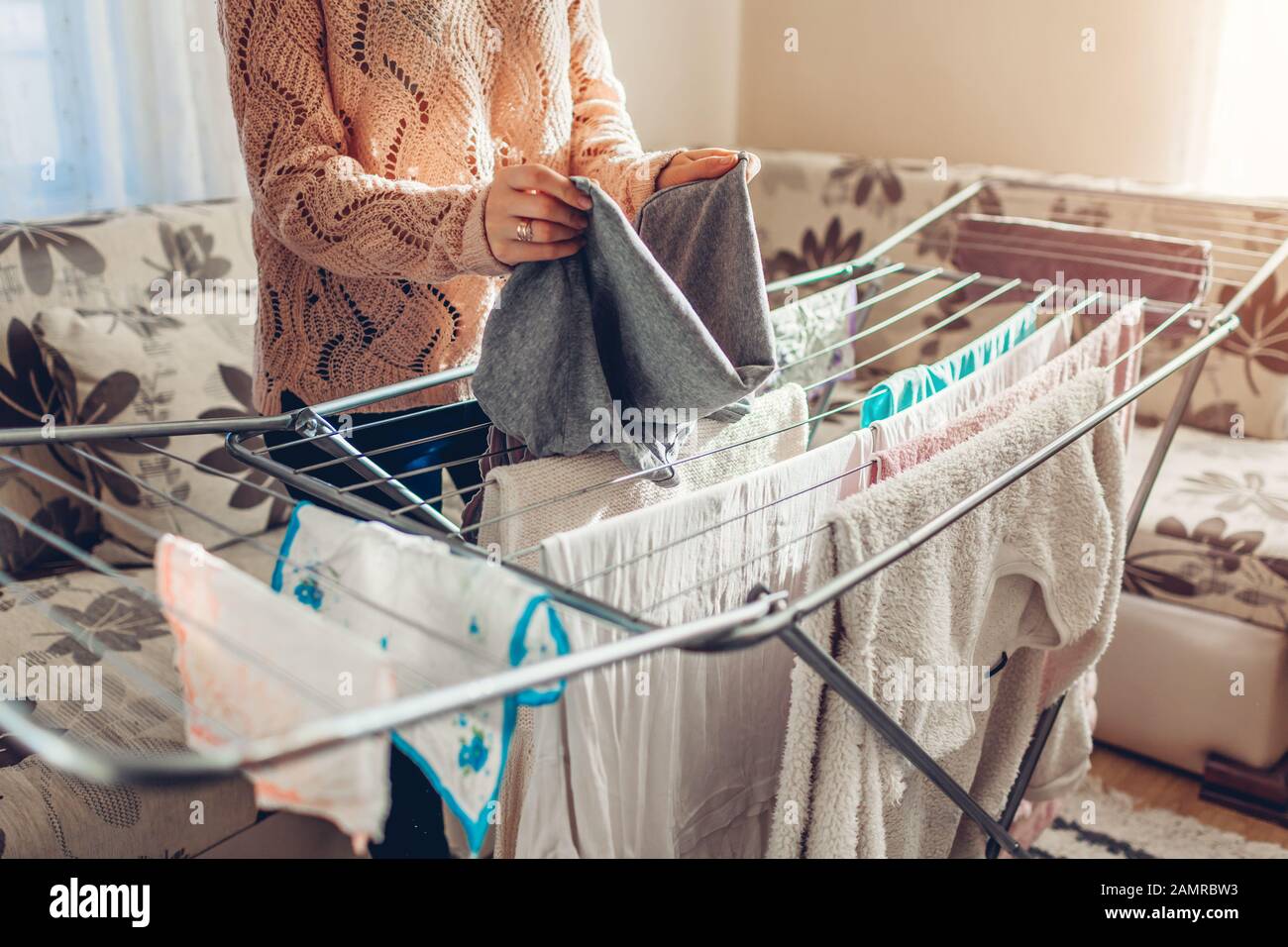 Woman folding gathering clean clothes from dryer after washing at home