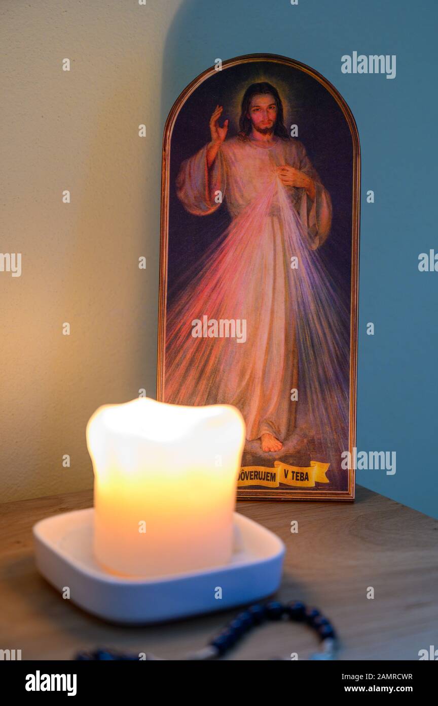 A picture of the Merciful Jesus with a lit candle and rosary in front of it. A private chapel. Stock Photo