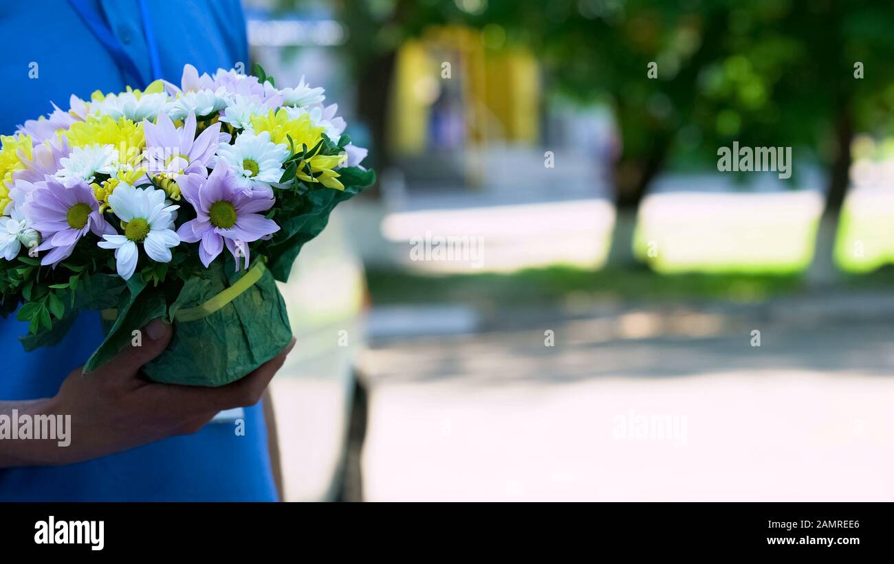 Male courier holding beautiful bouquet, express flowers order and delivery Stock Photo