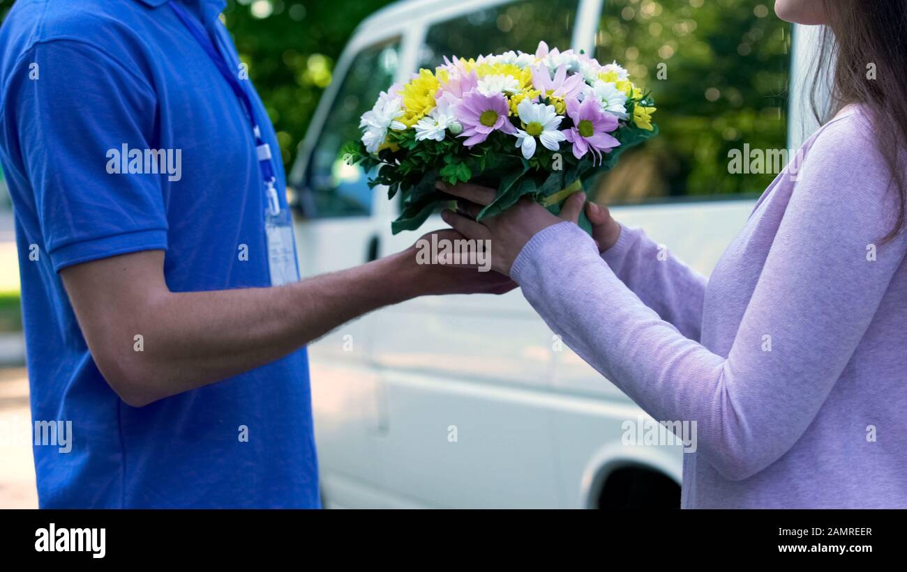 Surprised woman taking bouquet from couriers hands, flower shop