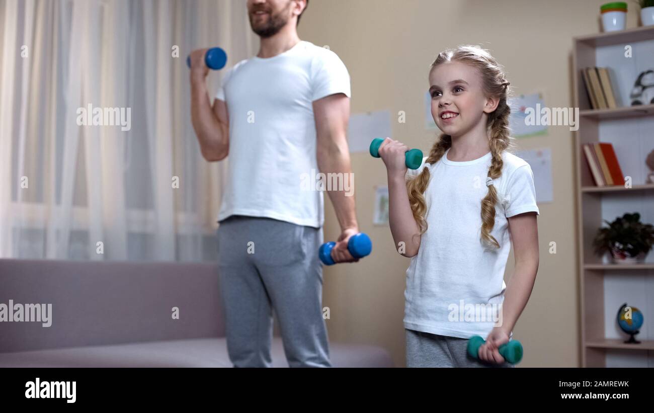 Daughter and father training with dumbbells at home, fitness family ...