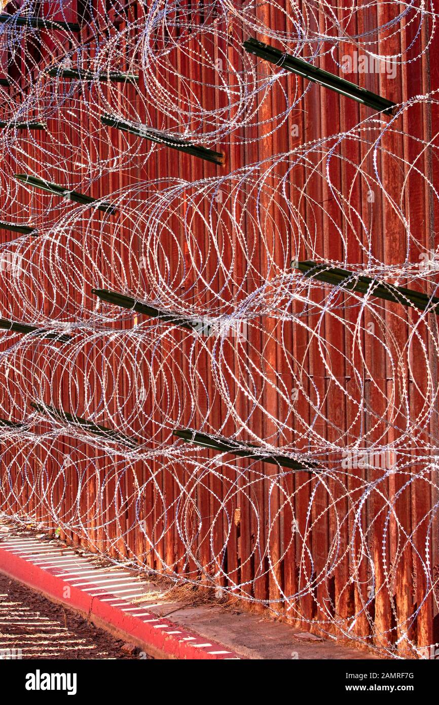 The USMexican border wall with layers of razor wire at Nogales AZ