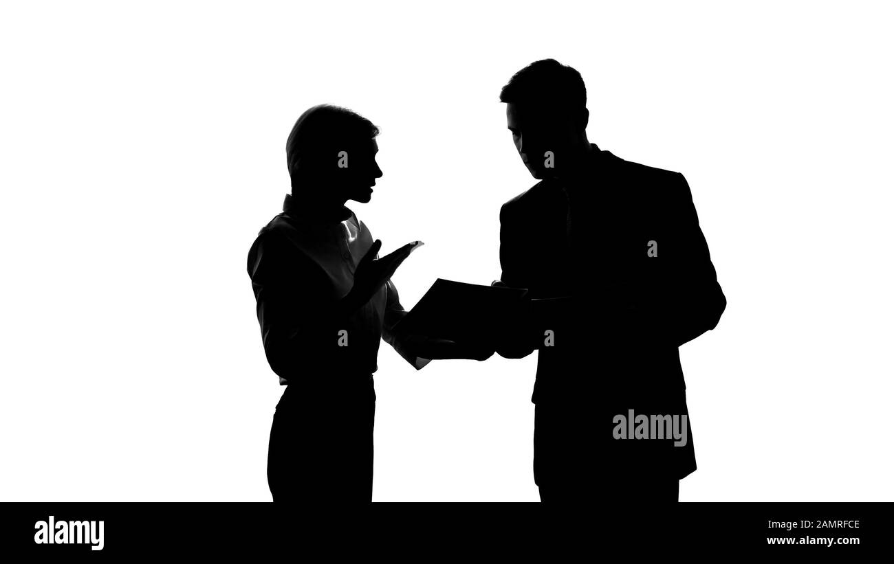 Male and female colleague silhouettes arguing over business documents in office Stock Photo