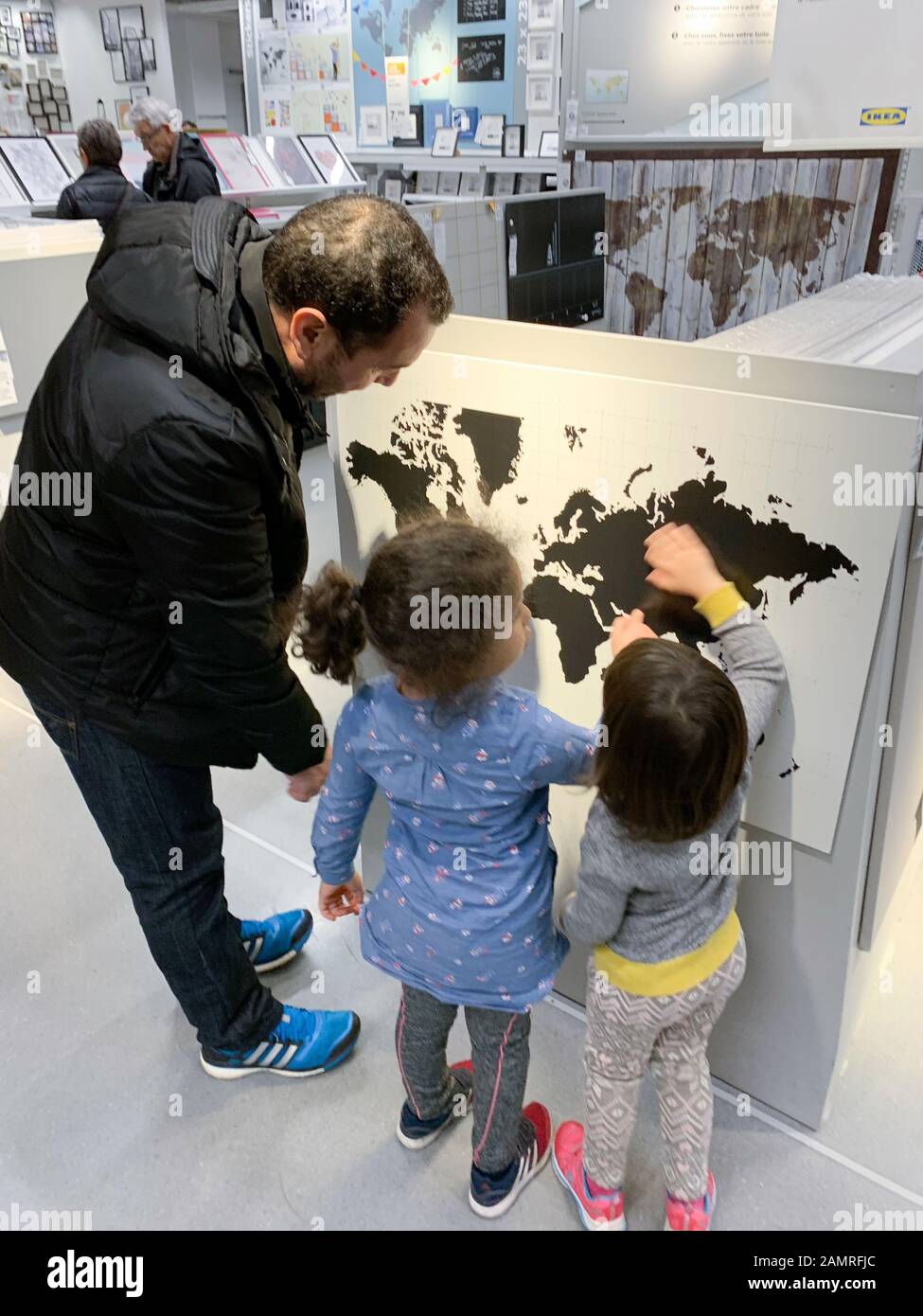 Paris, France - Dec 1, 2018: Busy atmosphere inside IKEA furniture store with customers choosing the right objects father explaining to girls the world map Stock Photo