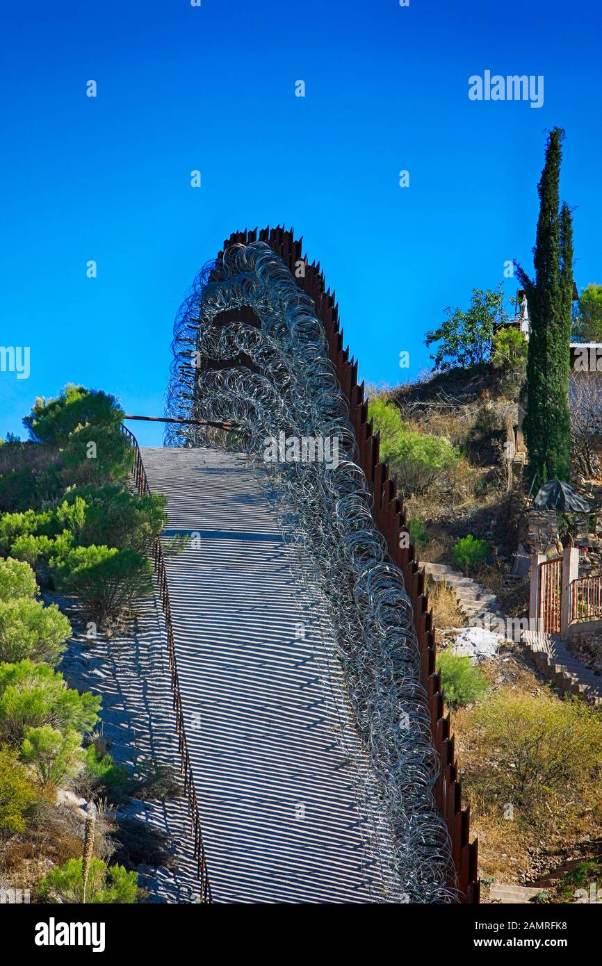 The USMexican border wall with layers of razor wire at Nogales AZ