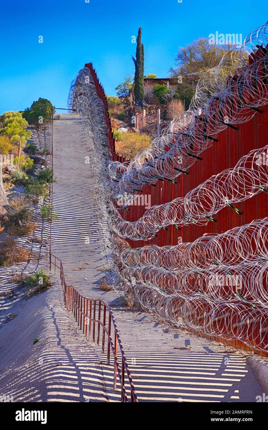 The USMexican border wall with layers of razor wire at Nogales AZ