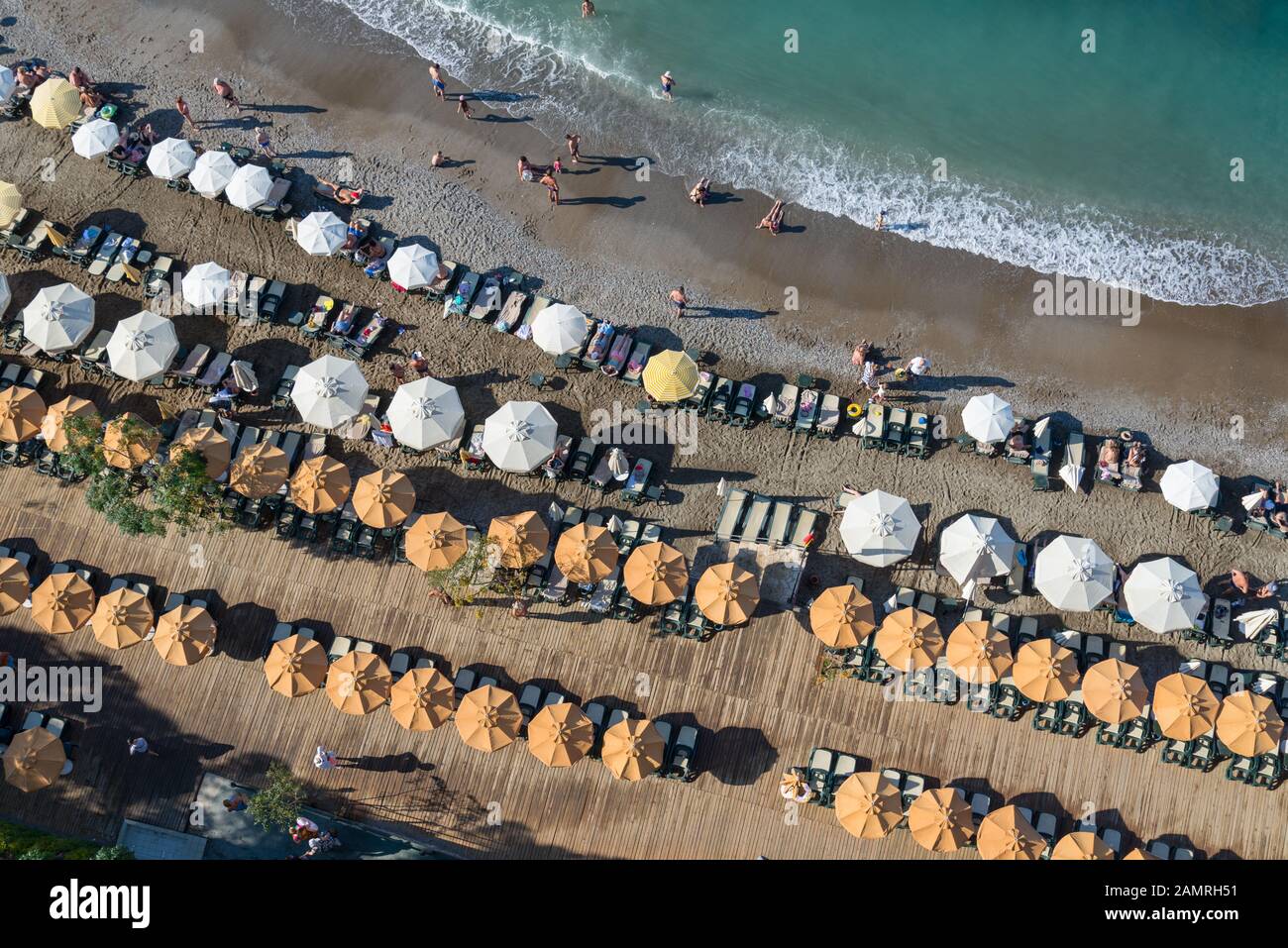 Turkish beach filled with holidaymakers, rows of sun loungers and parasols Stock Photo