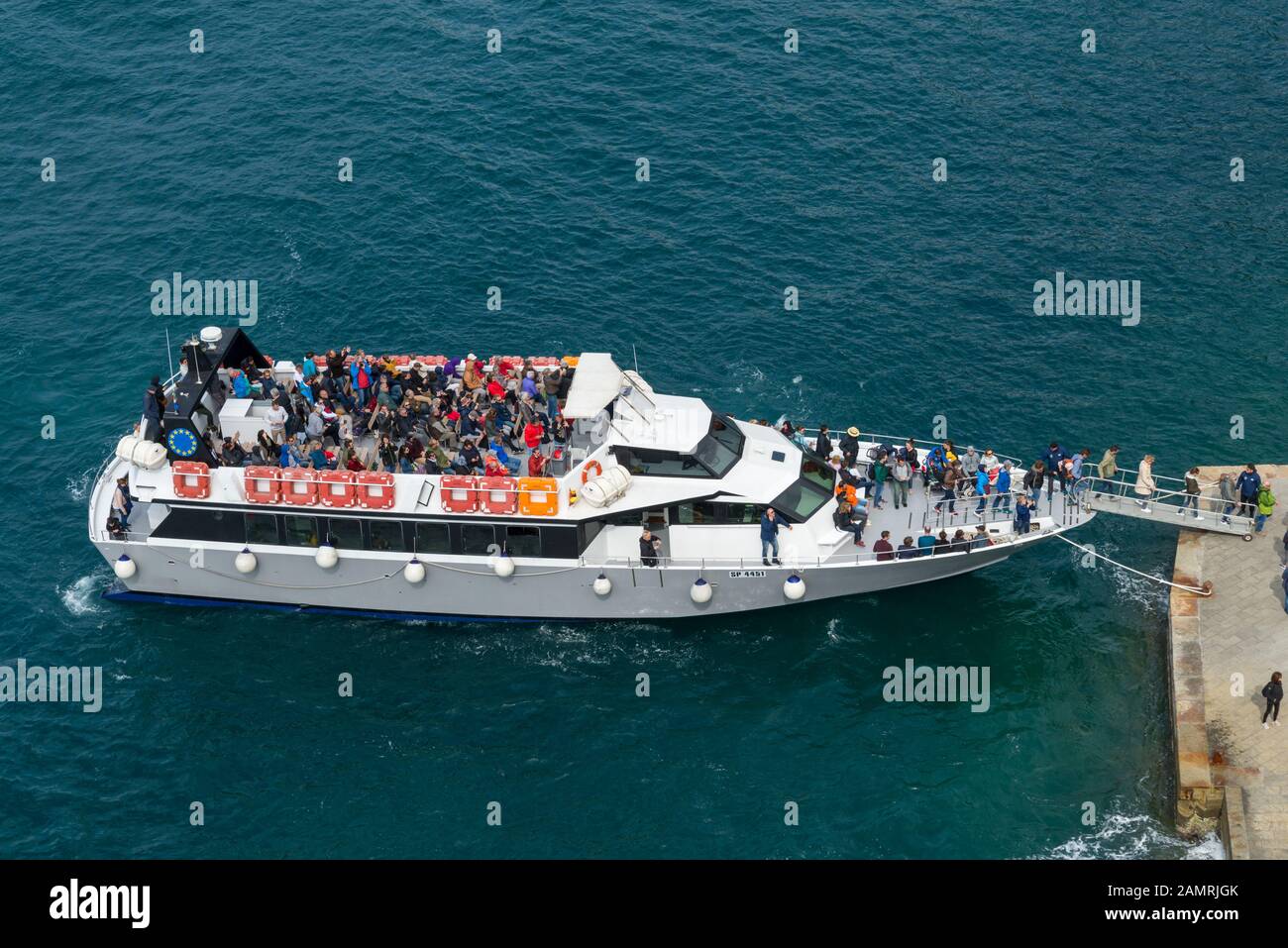 Tourists land and board in the excursion boat to the pier of Vernazza town. Stock Photo