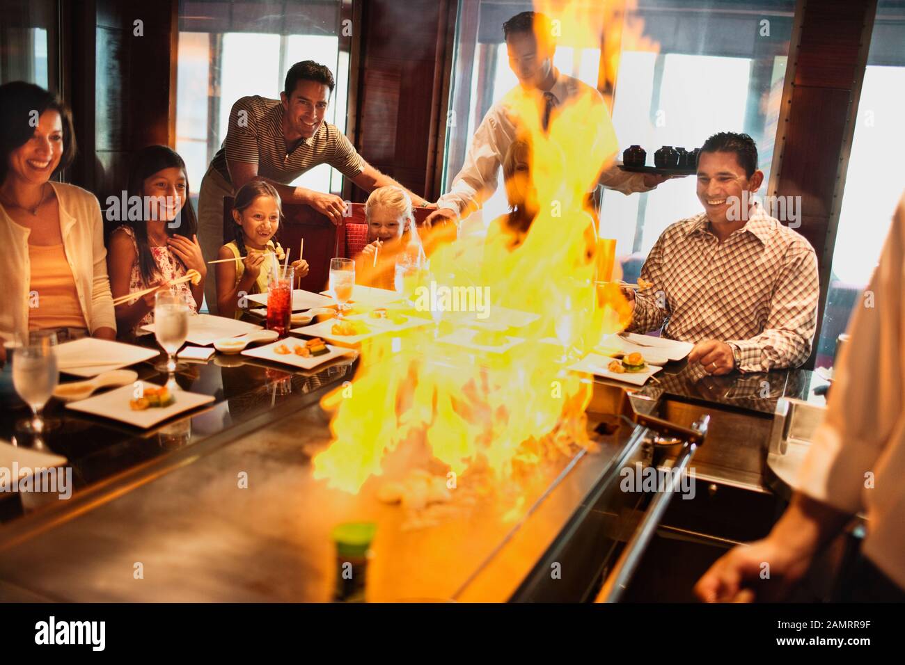 Family At A Japanese Teppanyaki Restaurant Watching The Chef Fire The 