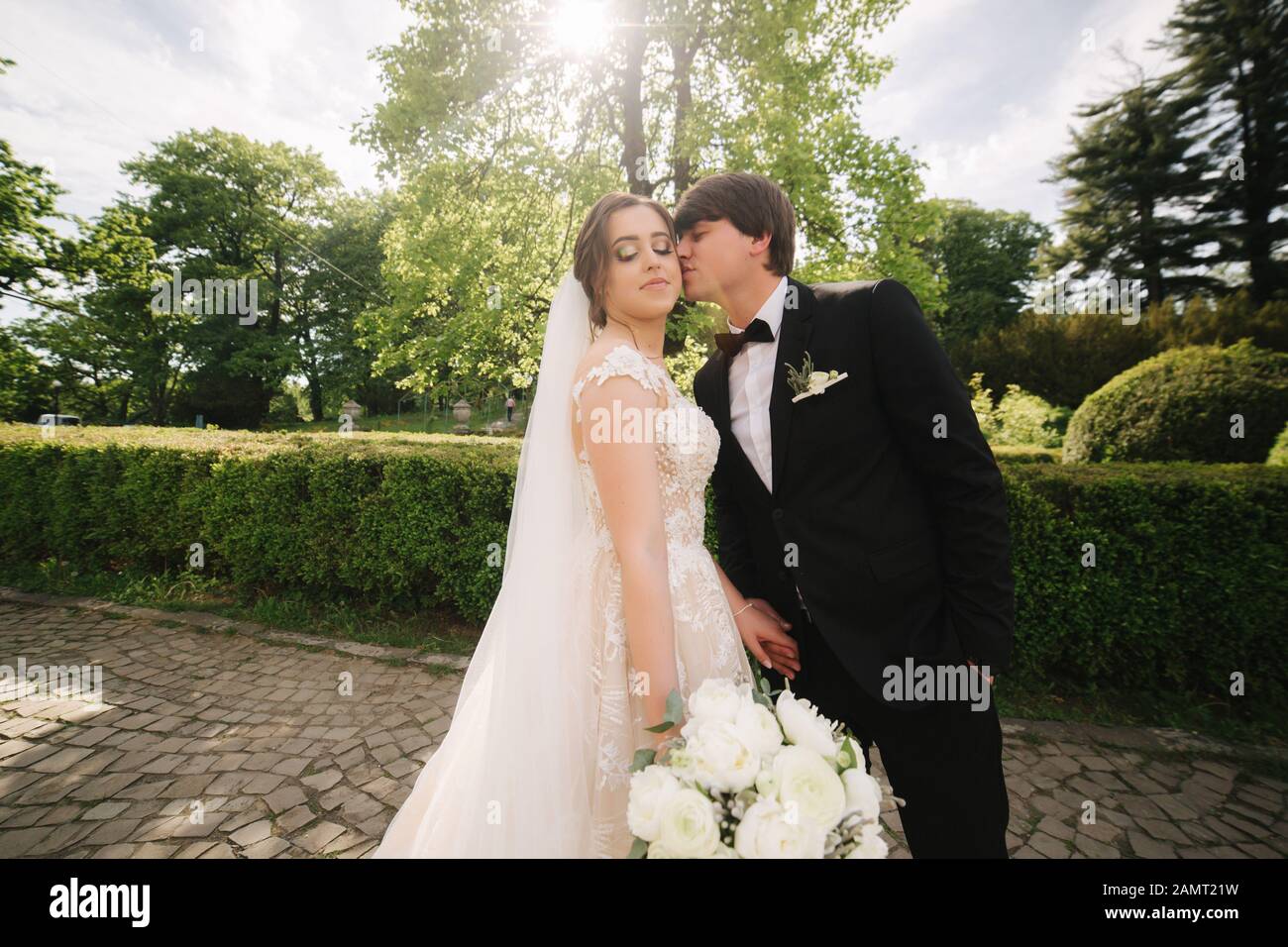 Groom and bride standing by the big tree in the park Stock Photo - Alamy