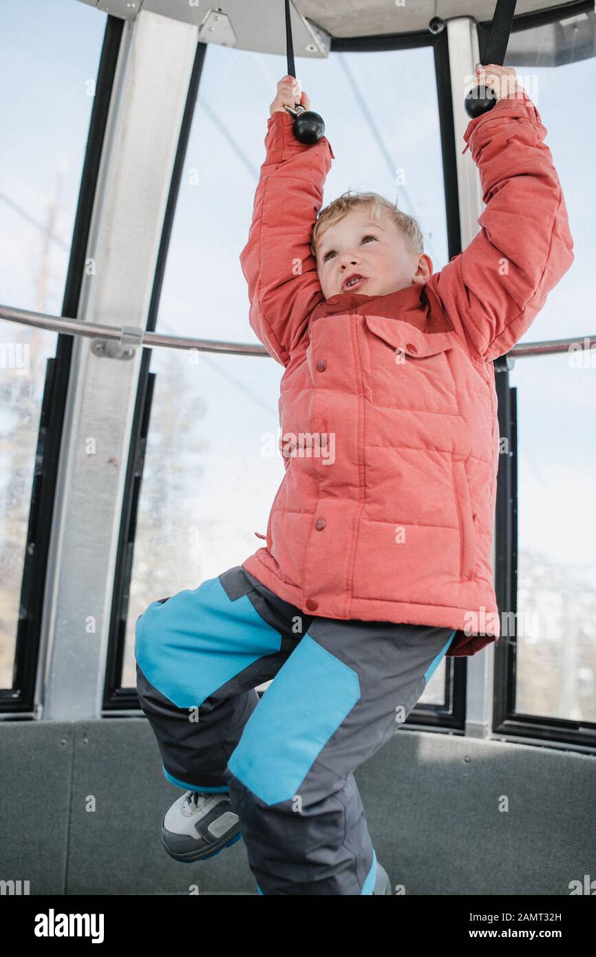 Boy in an overhead cable car holding onto handles, Mammoth Lakes, California, USA Stock Photo