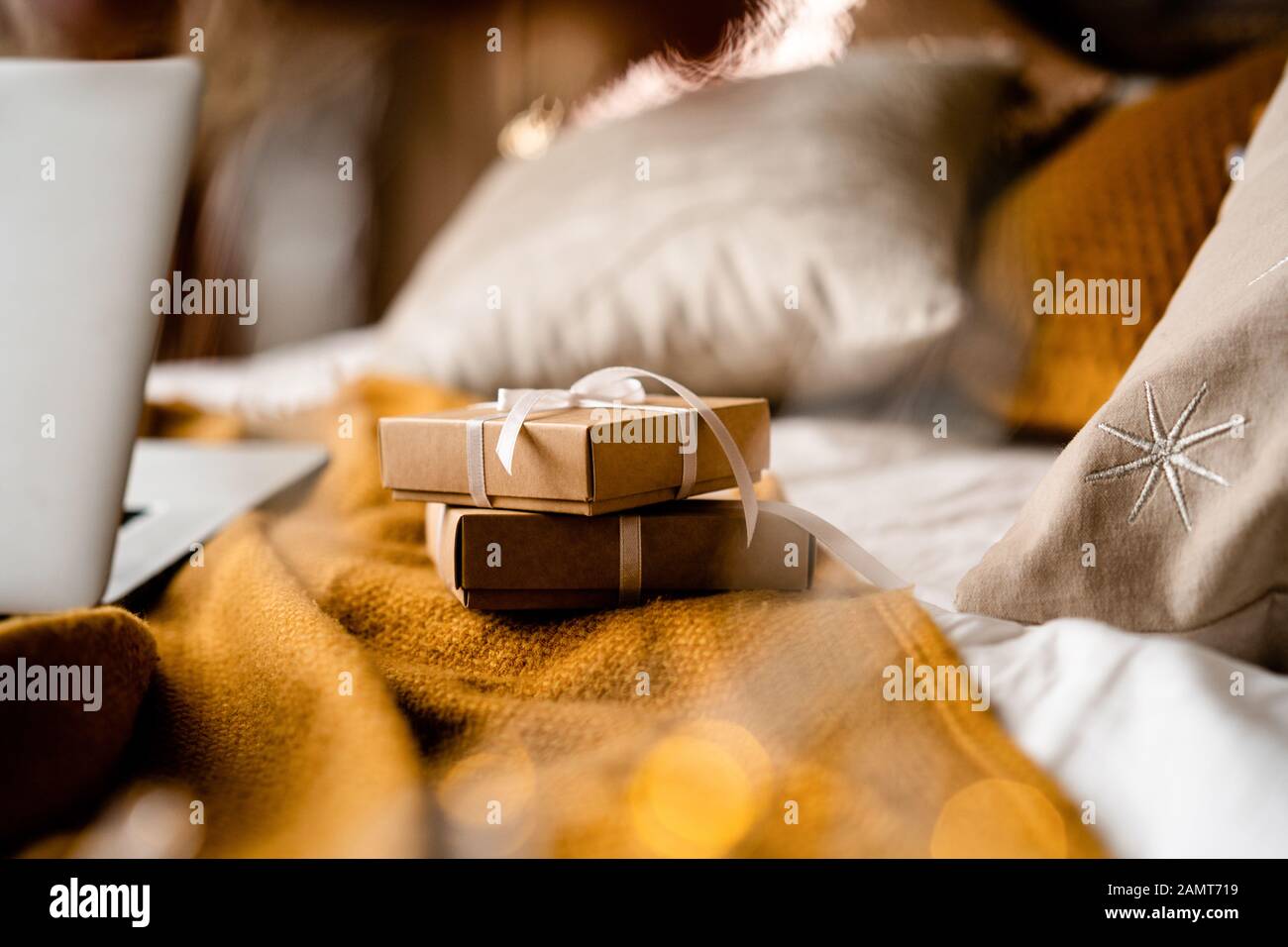 Gift boxes on a bed next to a laptop computer Stock Photo