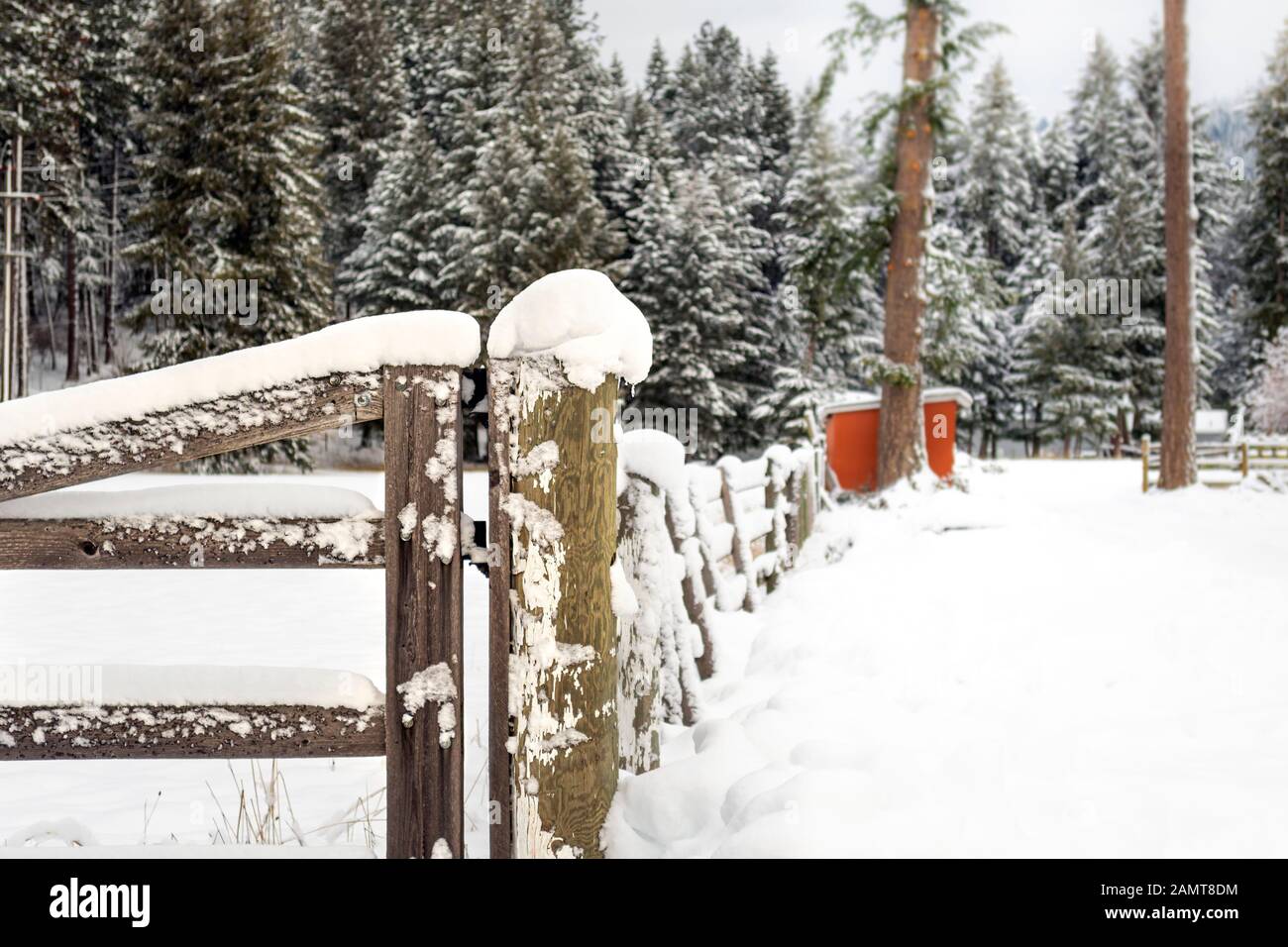 A wooden fence post covered in snow during winter in the rural mountains of North Idaho, USA Stock Photo
