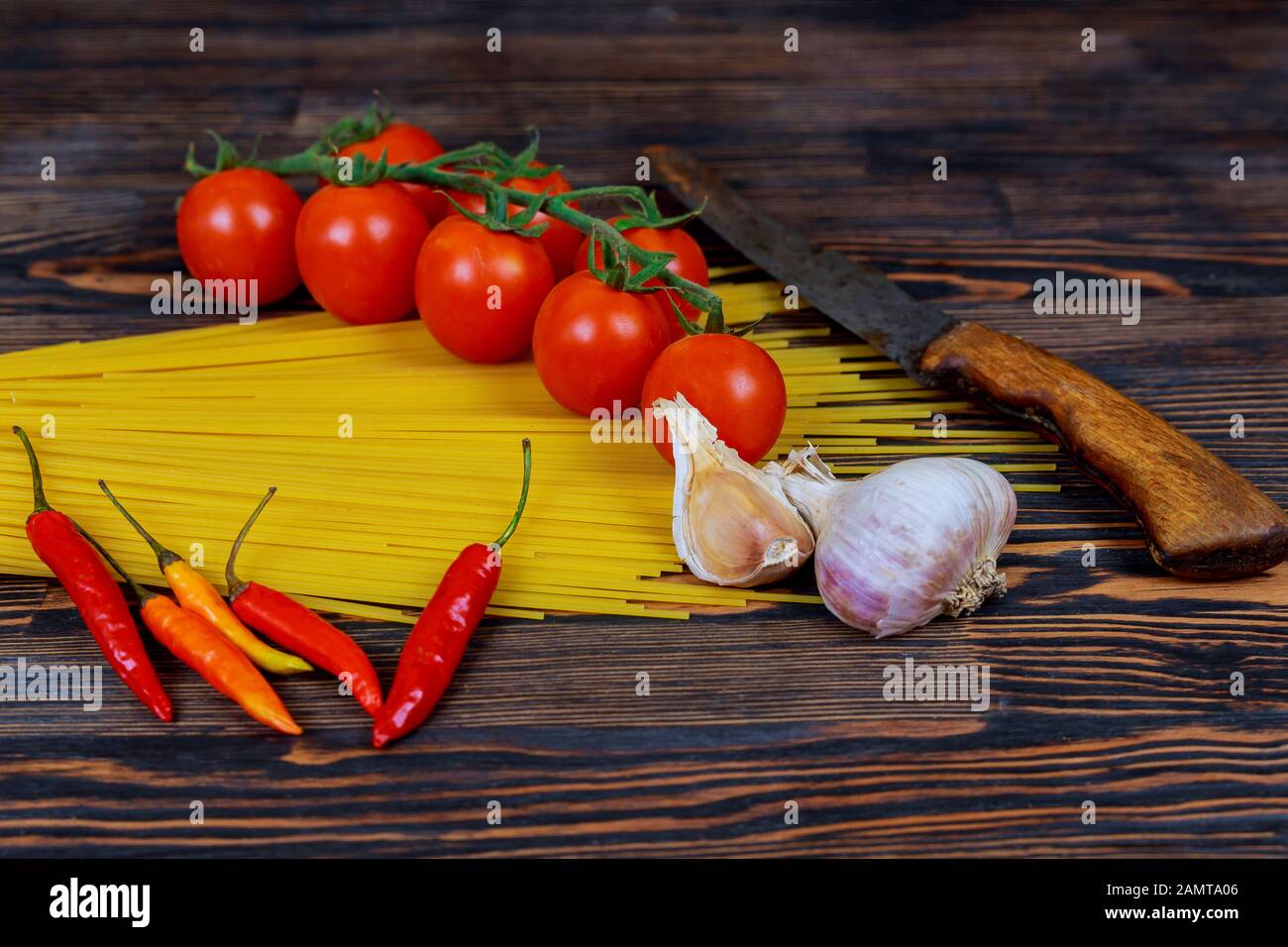 Raw pasta spaghetti with tomatoes, chili pepper and whole garlic Stock ...