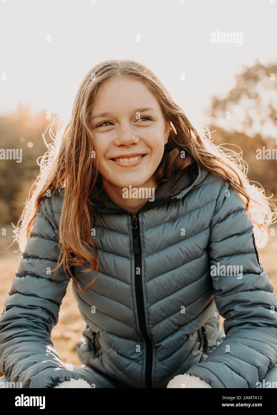 Portrait of a smiling girl sitting in the autumn sun, Netherlands Stock Photo