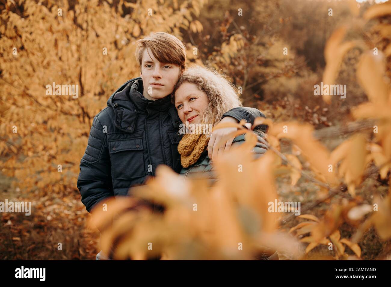 Mother standing in an autumn woodland hugging her son, Netherlands Stock Photo