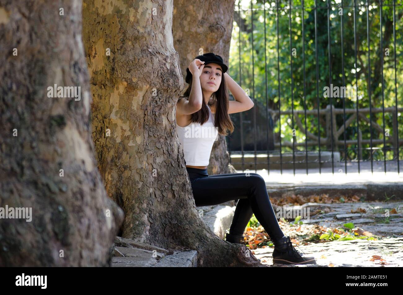 Teenage girl sitting on the curb between trees, Argentina Stock Photo