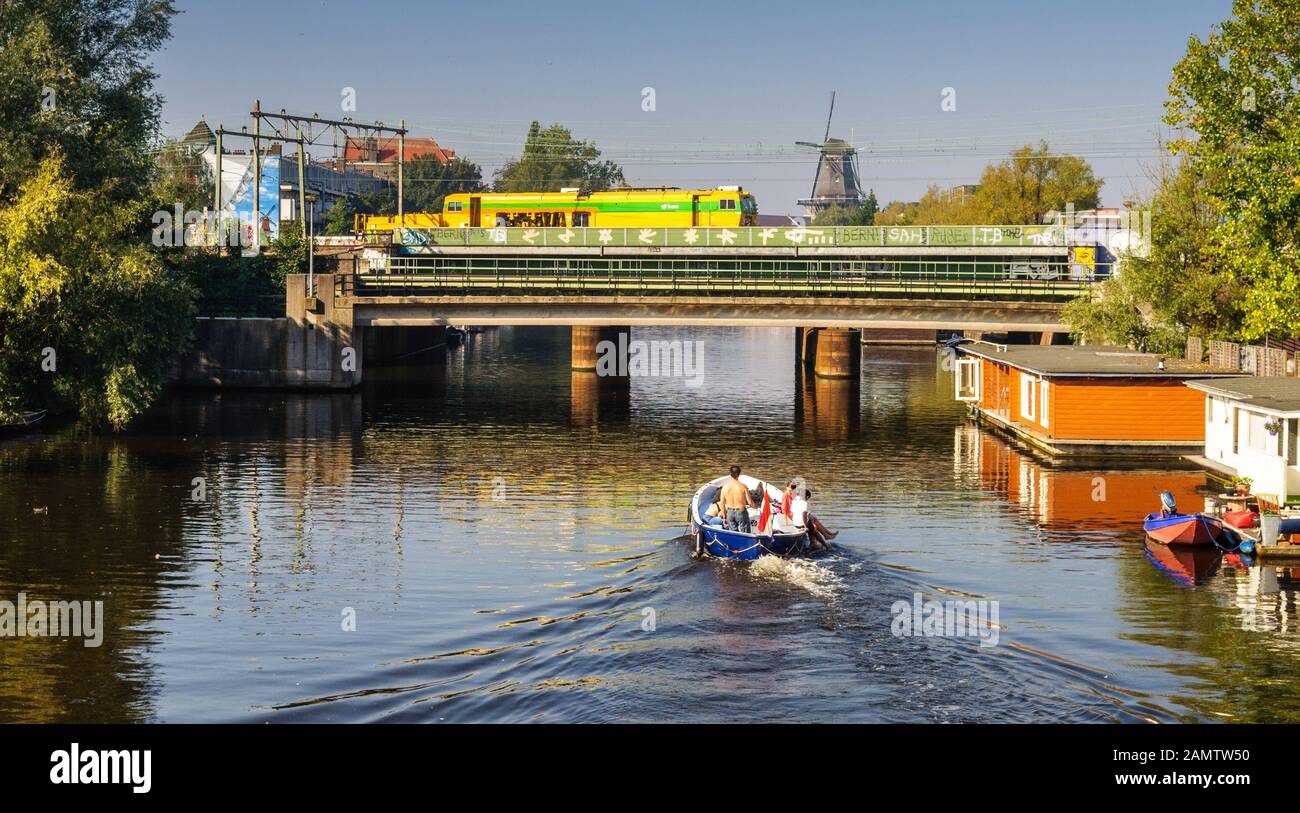 Amsterdam, Netherlands - October 2, 2011: A family take a small recreational boat along the Lozingskanaal and under the Amsterdam-Arnhem Railway in th Stock Photo