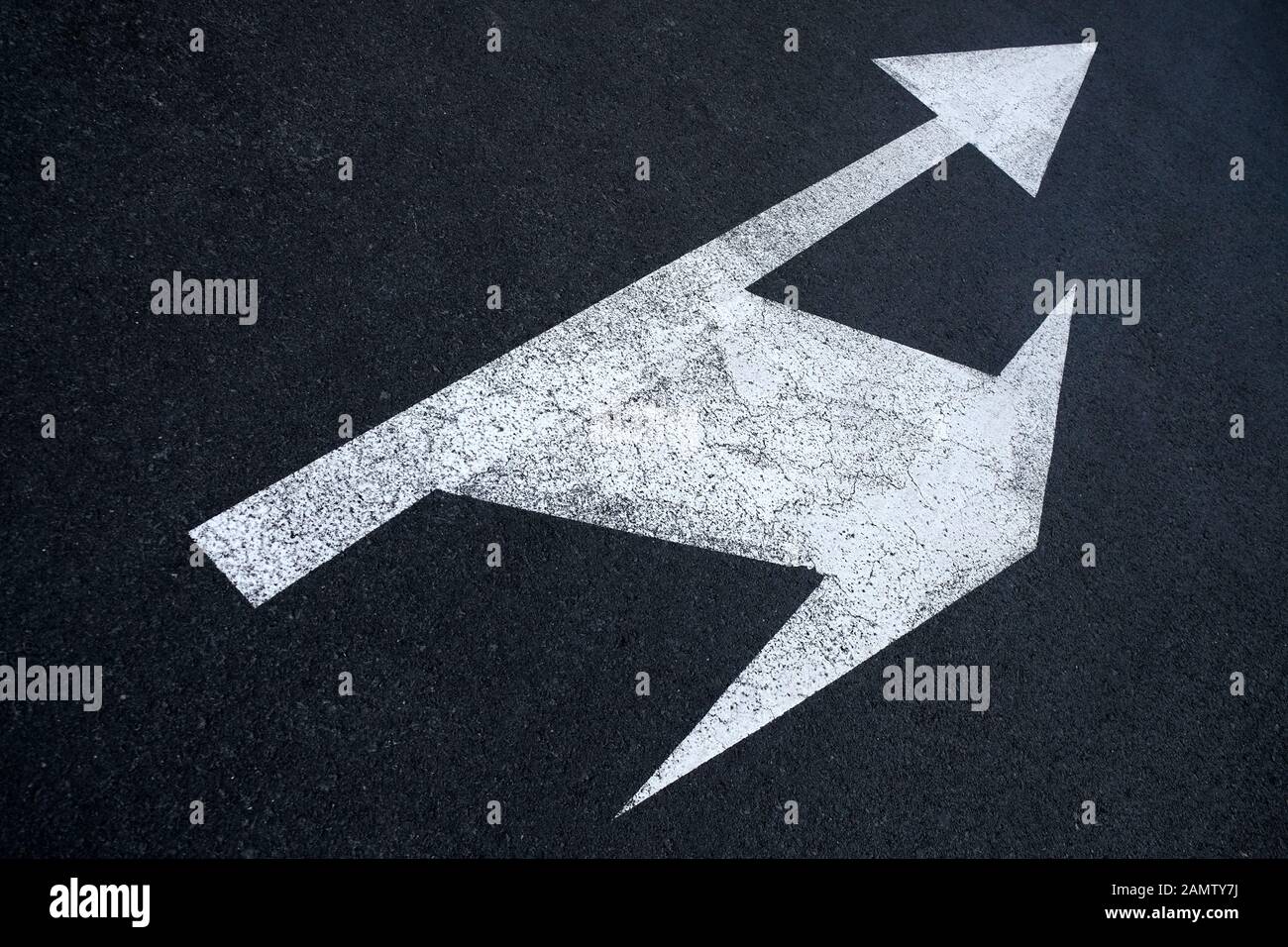 Split arrows directions icon painted on black pavement. Stock Photo