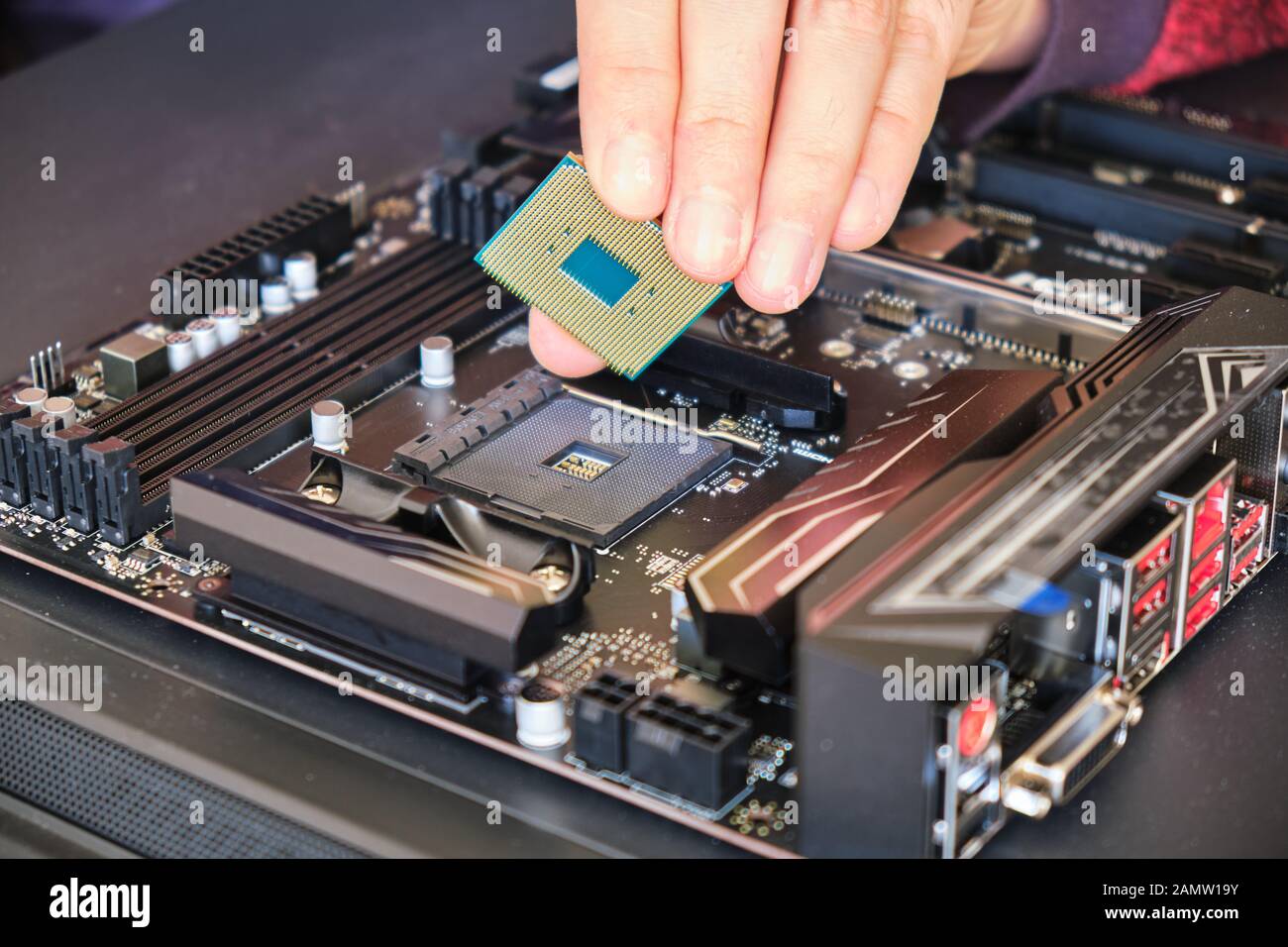 Placing a computer chip (CPU) in its socket on a black motherboard. Custom PC build. Stock Photo