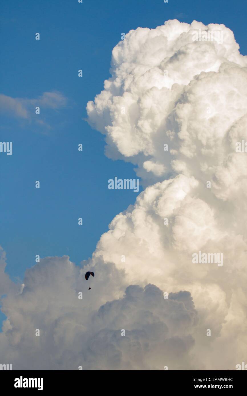 cumulonimbus cloud powerful high white cumulus and paragliding against a blue sky Stock Photo