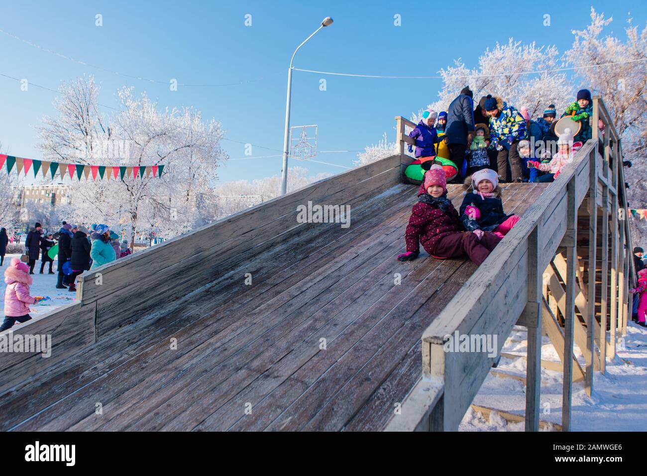 Novokuznetsk, Russia- January 07, 2019: Russian winter entertainment: children having fun tobogganing from wooden toboggan Stock Photo