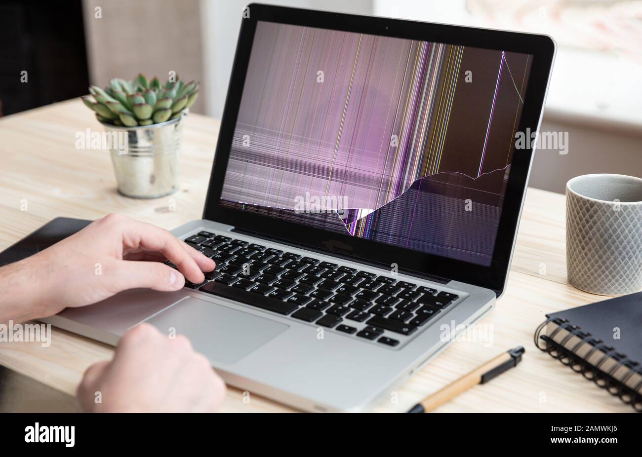 Broken laptop repair, insurance concept. Man working with a computer with damaged screen, office business background. Stock Photo