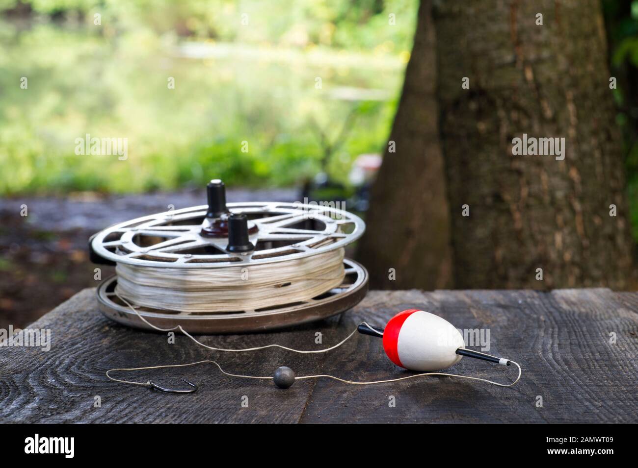 Fishing reel with fishing line, red and white float, hook and sinker on  wooden table on natural background. The concept of classic fishing tackle.  Tex Stock Photo - Alamy