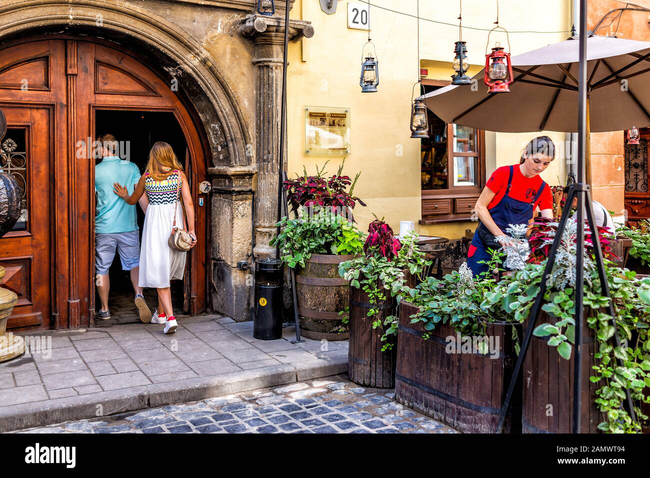 Lviv, Ukraine - August 1, 2018: Street in historic Ukrainian Lvov city during day with yellow old vintage buildings in old town people couple entering Stock Photo