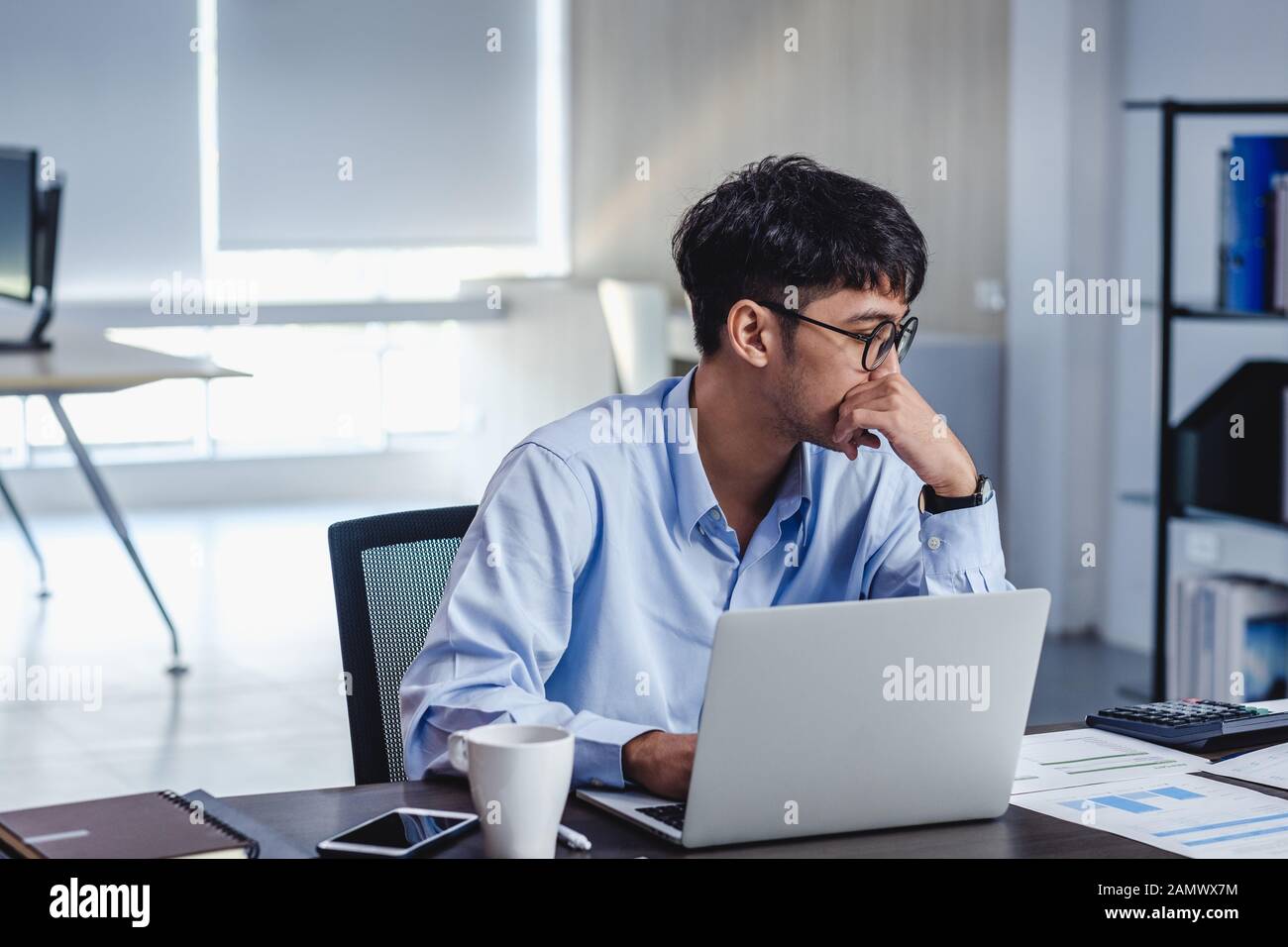 asian businessman get stress and thinking when working with laptop on desk  at modern office.business fail concept.man rest hand on chin on table when  Stock Photo - Alamy