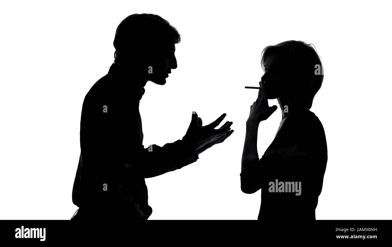 Angry man shouting at his girlfriend smoking cigarette in front of him, quarrel Stock Photo