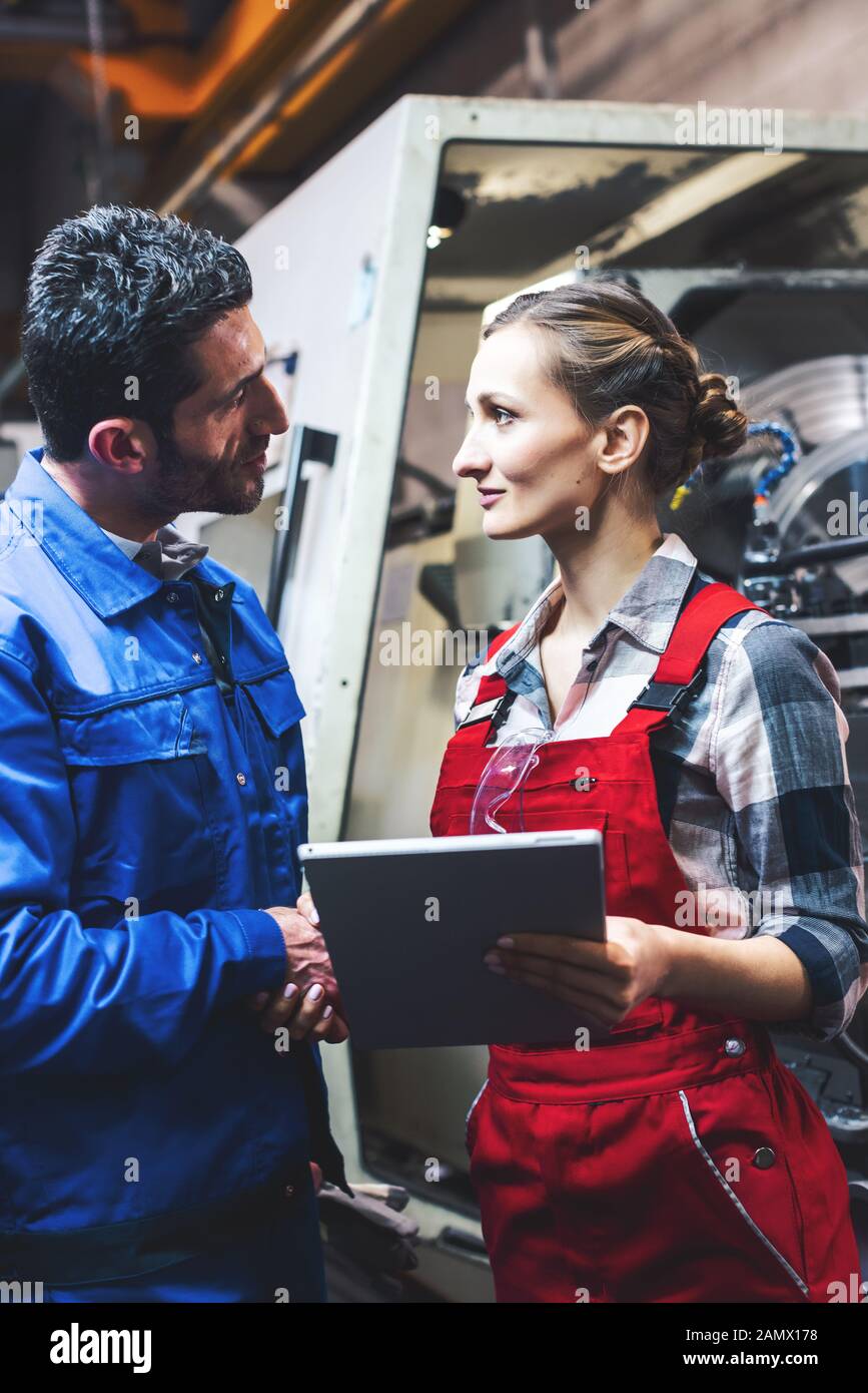 Woman and man manufacturing worker in discussion Stock Photo