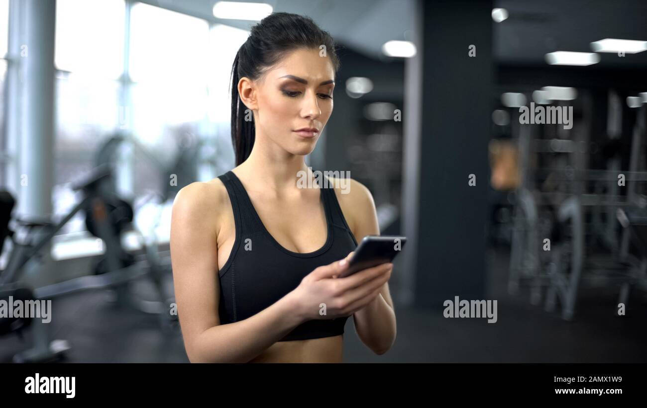Purposeful lady in sportswear scrolling smartphone application, motivation Stock Photo