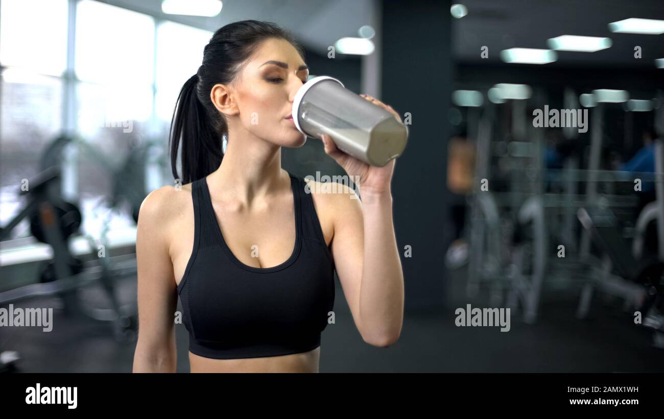 Sporty woman drinking protein shake after workout, muscle gain nutrition, health Stock Photo