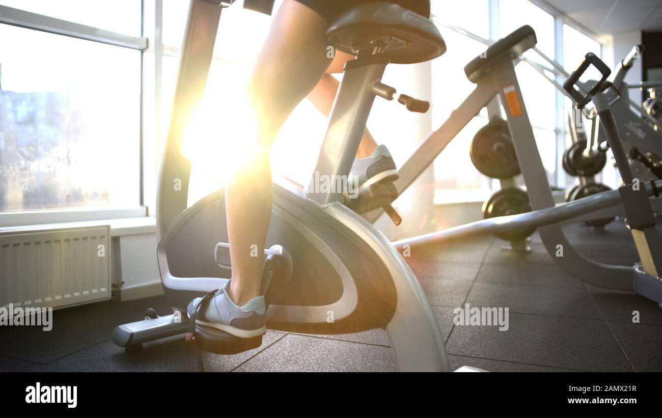 Female legs training on stationary bike, burning calories, cardio