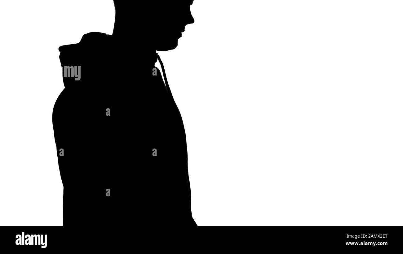 Shadow of male wearing hoodie standing on white background, silhouette Stock Photo