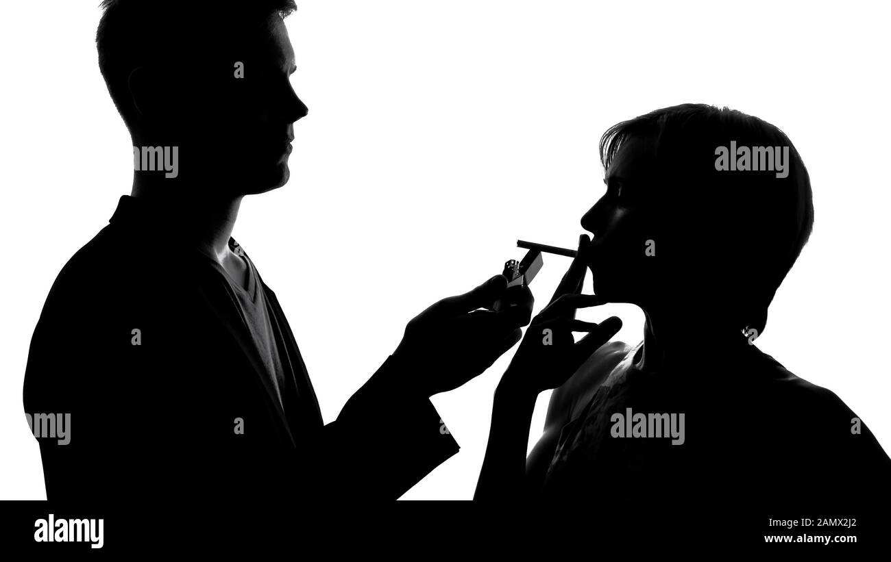Silhouette of male walking to female and lighting her cigarette, flirt at  party Stock Photo