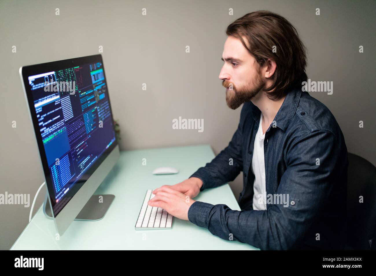 Male programmer working on desktop computer at white desk in office ...