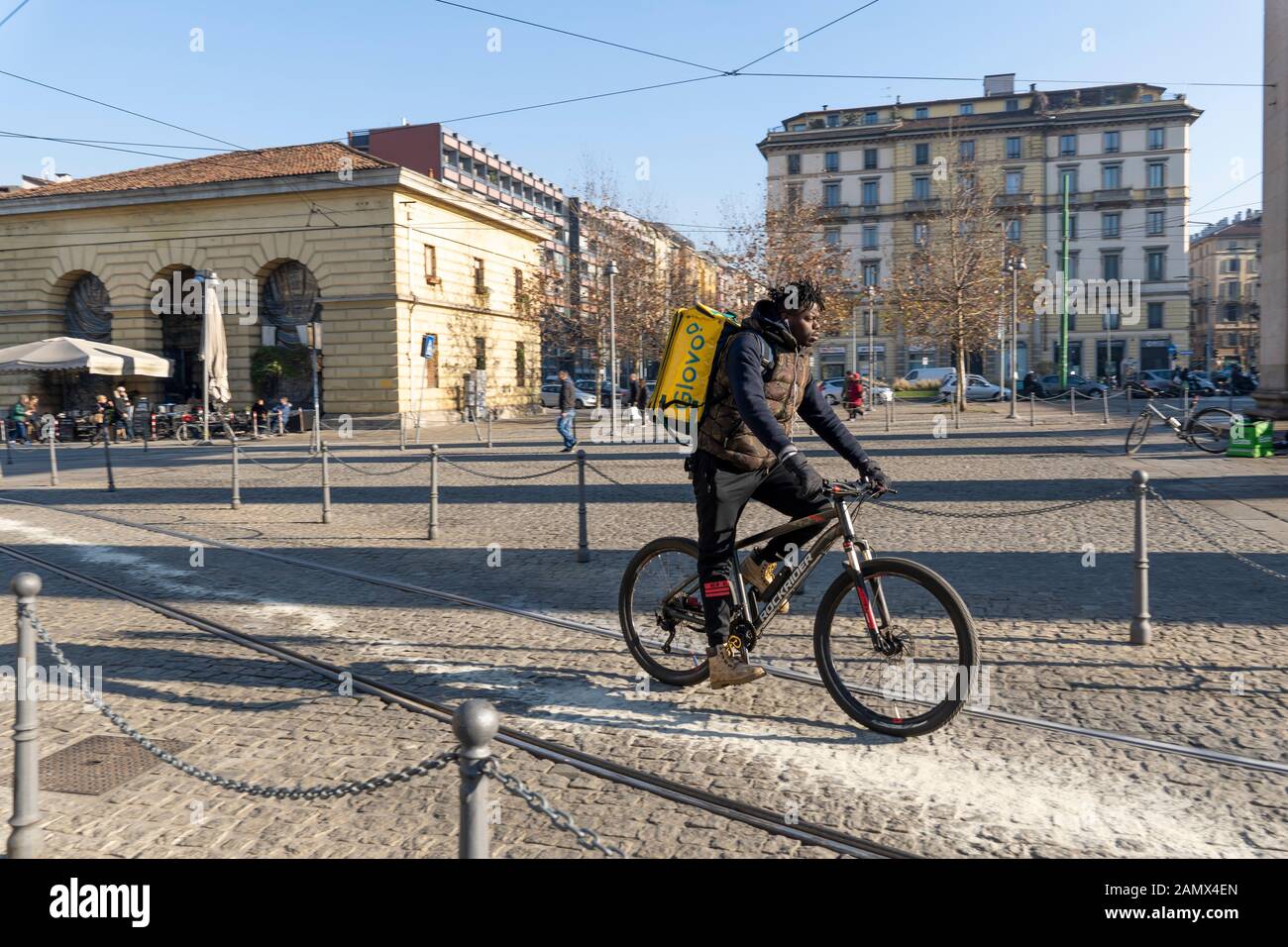 Milan, Italy - January 11, 2020: A Glovo rider cycles on a city centre street. Food delivery service. Online ordering. Stock Photo