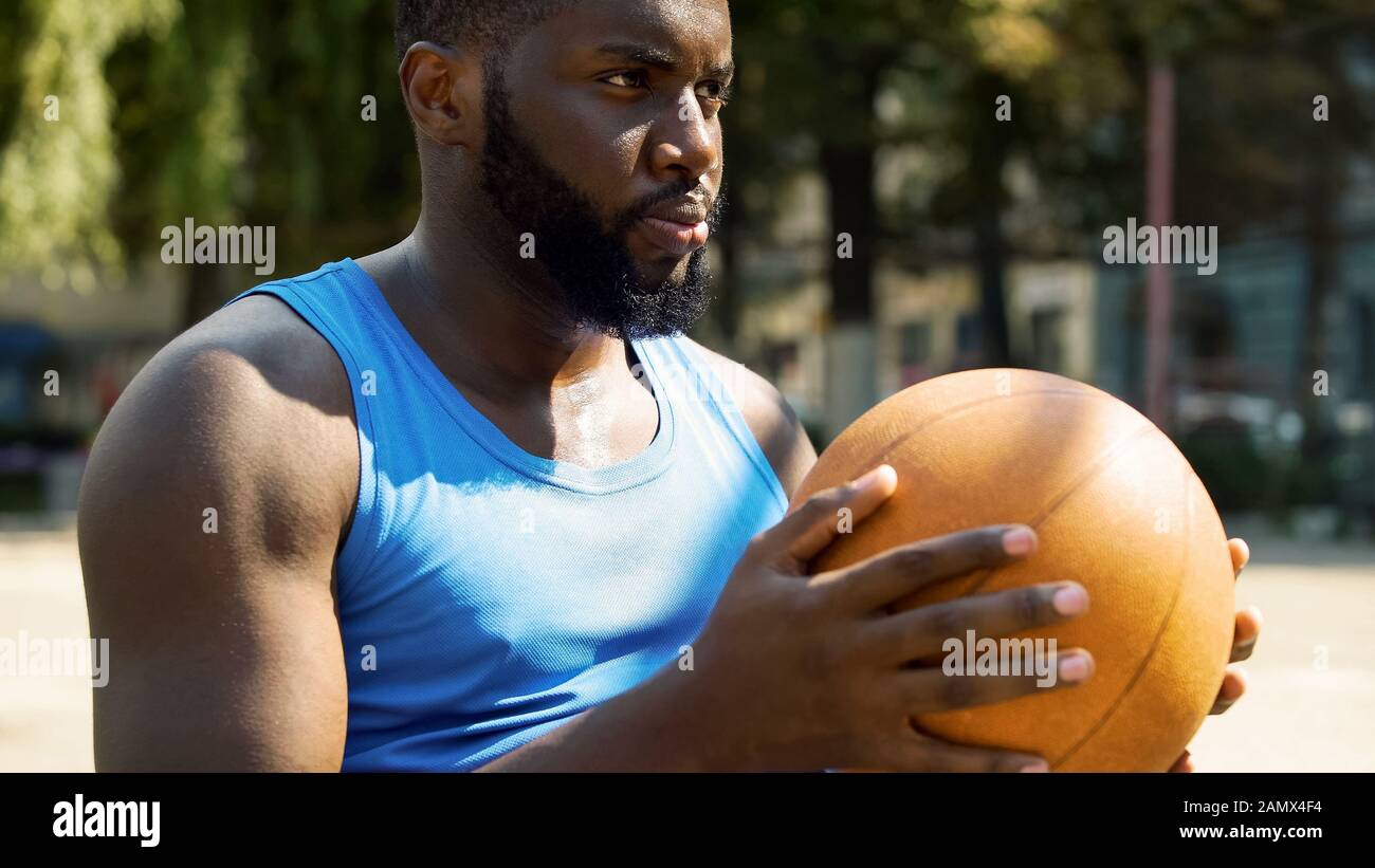 Athletic African-American basketball player holding ball, preparing for game Stock Photo