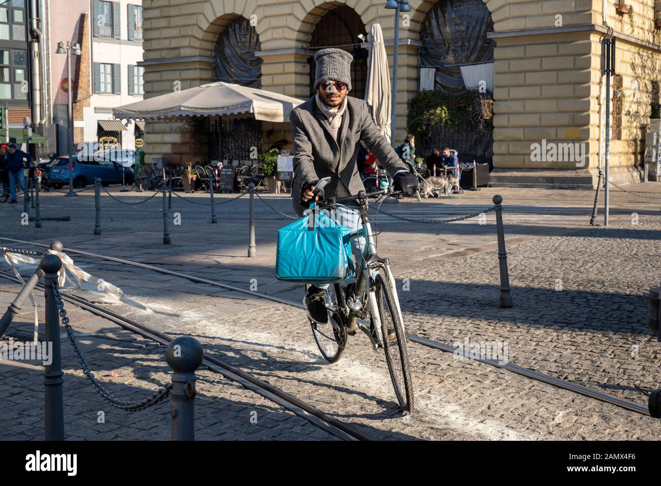 Milan, Italy - January 11, 2020: A very stylish Deliveroo courier on bike deliver tasty food in a city centre street. City Food delivery service. Onli Stock Photo