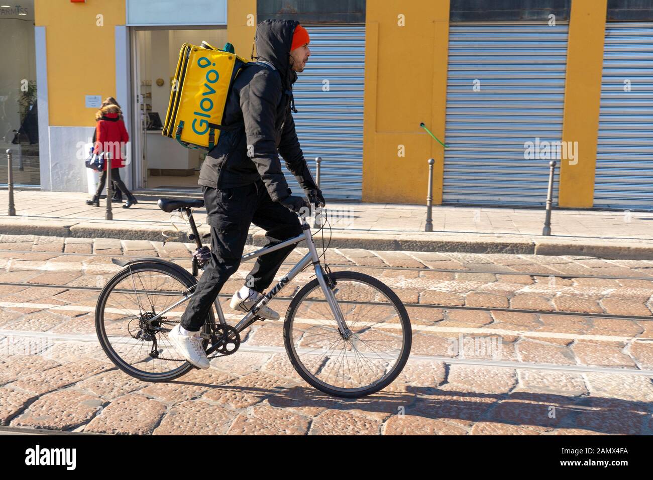 Milan, Italy January 11, 2020 A Glovo rider cycles on a city centre street. Food delivery