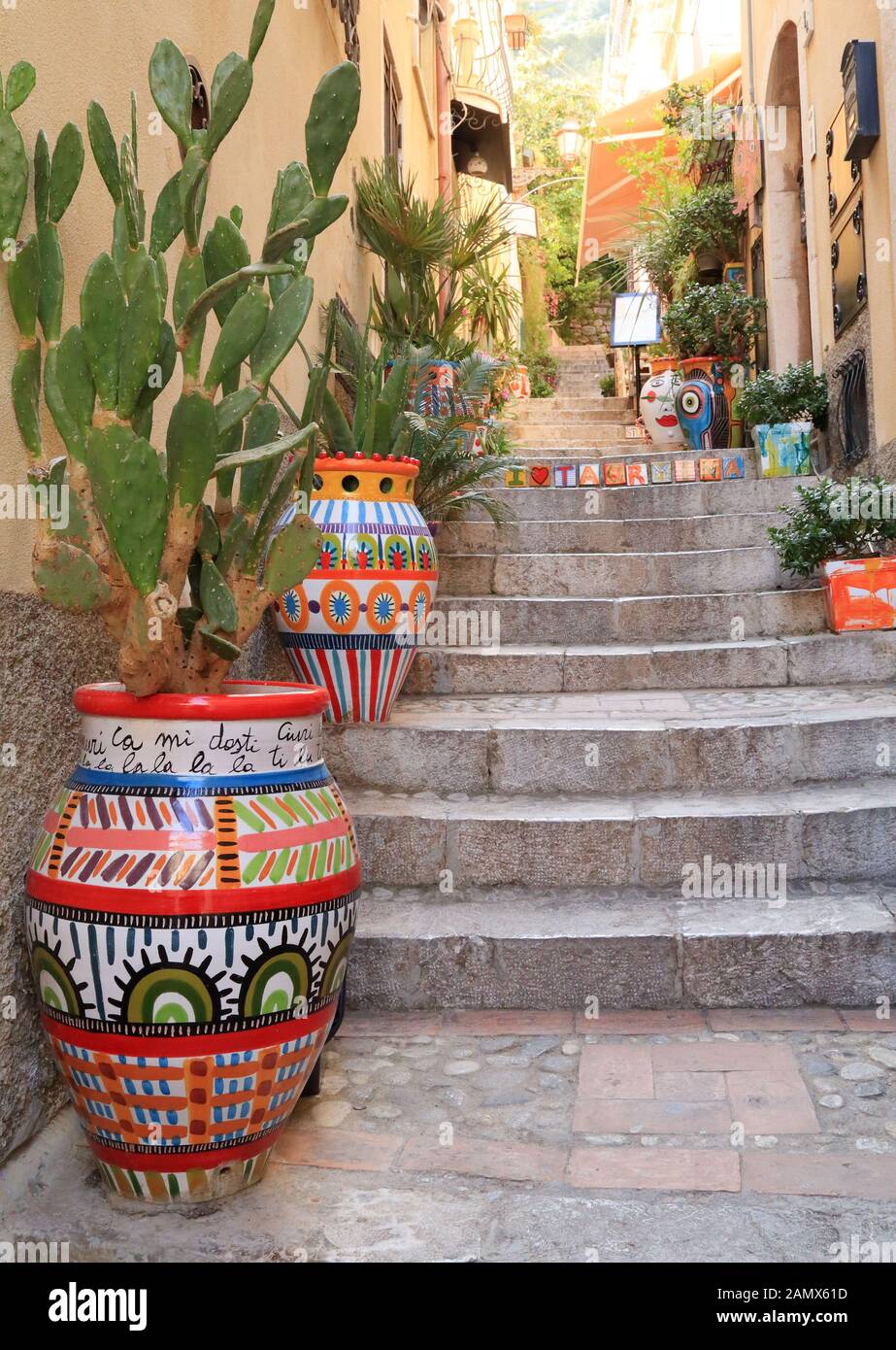 Narrow street with colorful flower pots in Taormina Stock Photo