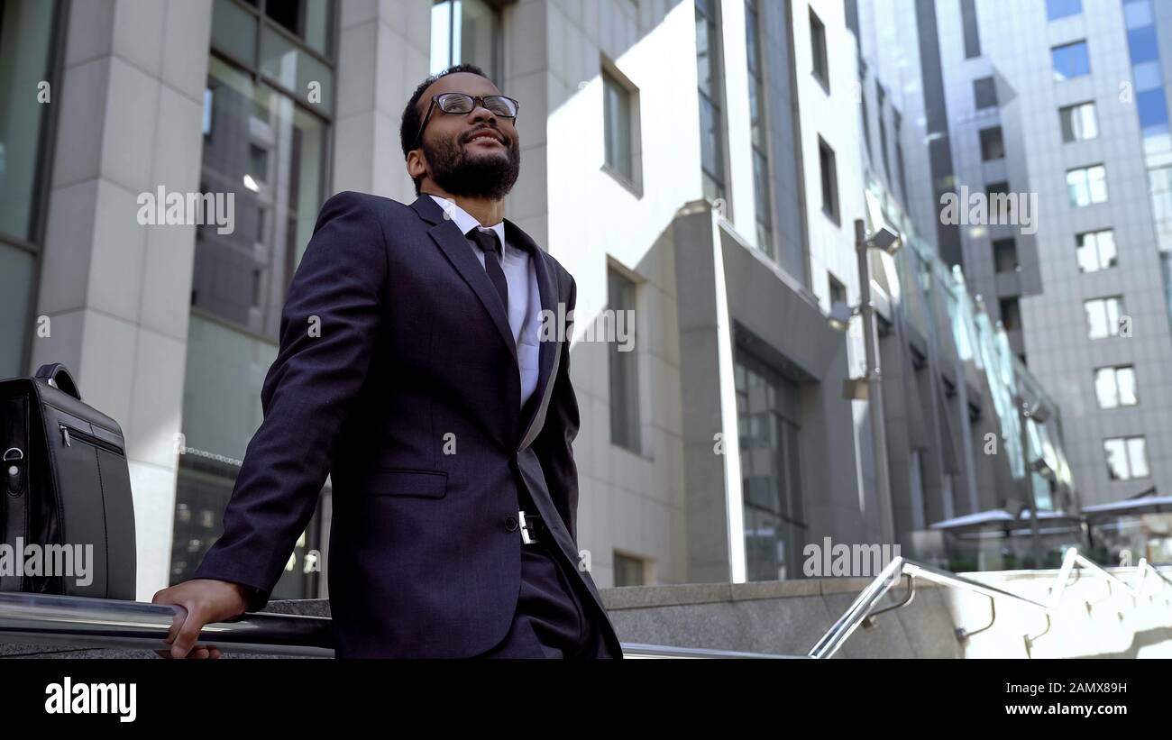 Afro-American employee standing on stairs near office building, prospects Stock Photo