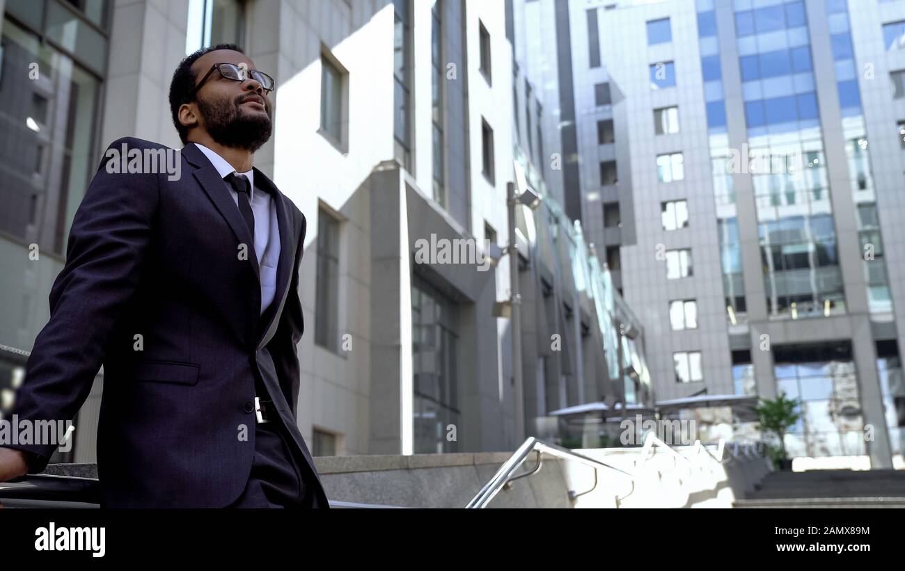 Mulatto businessman looking up, standing near office center opening new horizons Stock Photo