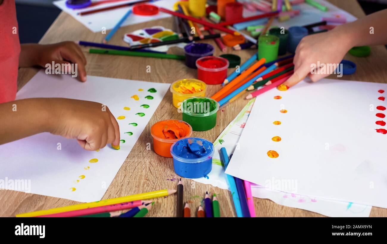 Children putting colorful dots on paper with fingers, painting a picture Stock Photo