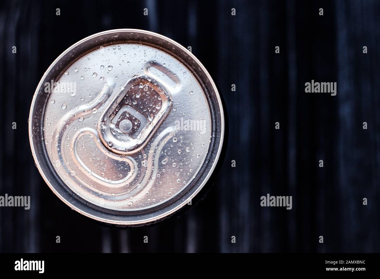 Beer can with condensation on black background. Aluminium can of drink with water drops, refrigerated cola can, top view. Text space Stock Photo